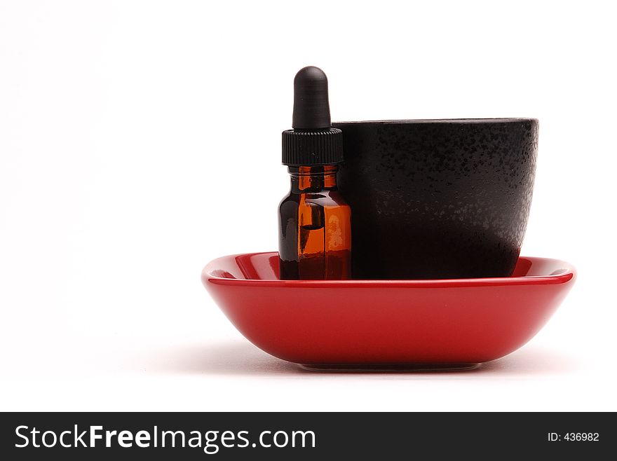 Red dish with a black bowl and an amber dropper bottle. Represents aromatherapy. Red dish with a black bowl and an amber dropper bottle. Represents aromatherapy.