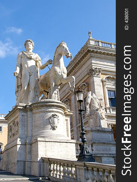 A statue of the mythological figure, Castor, and his horse outside an ornate building. A statue of the mythological figure, Castor, and his horse outside an ornate building.