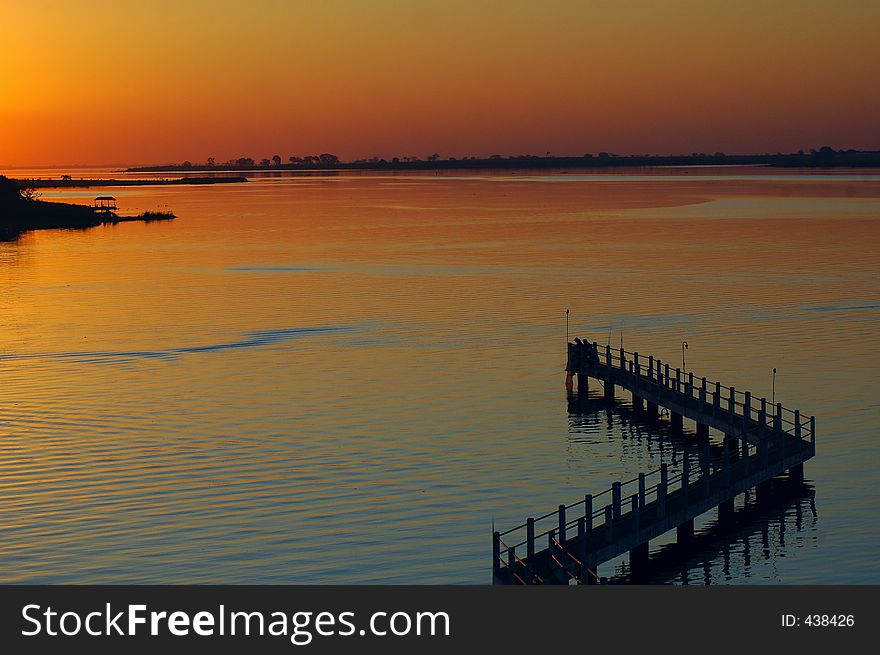 A sunset in a river with a bridge. A sunset in a river with a bridge