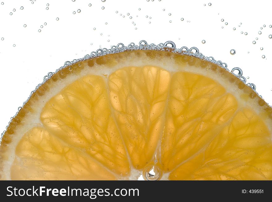 Slice of lemon backlit with bubbles against white background. Slice of lemon backlit with bubbles against white background