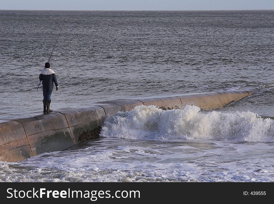 Man fishing on sea wall