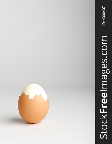 Partially peeled hard boiled egg on neutral background Think outside of the box. Partially peeled hard boiled egg on neutral background Think outside of the box