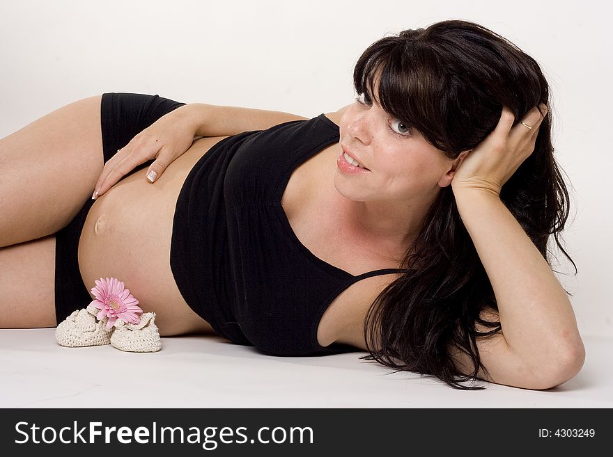 A pregnant woman with shoes and a flower in front of her. A pregnant woman with shoes and a flower in front of her