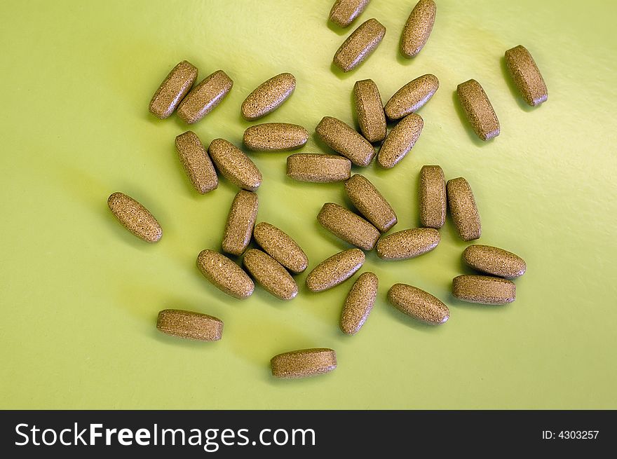 Brown pills on green background