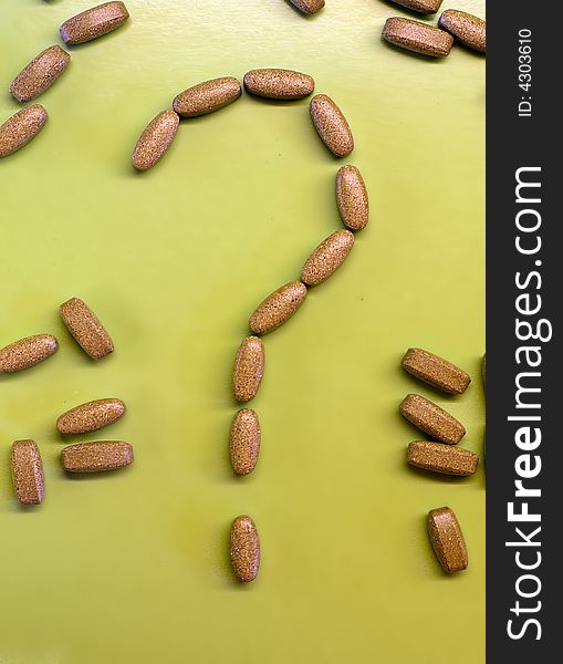 Brown pills on green background as a question mark. To eat or not to eat drugs.