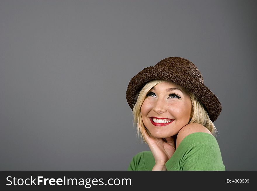 A blonde model in a brown hat smiling and looking up. A blonde model in a brown hat smiling and looking up
