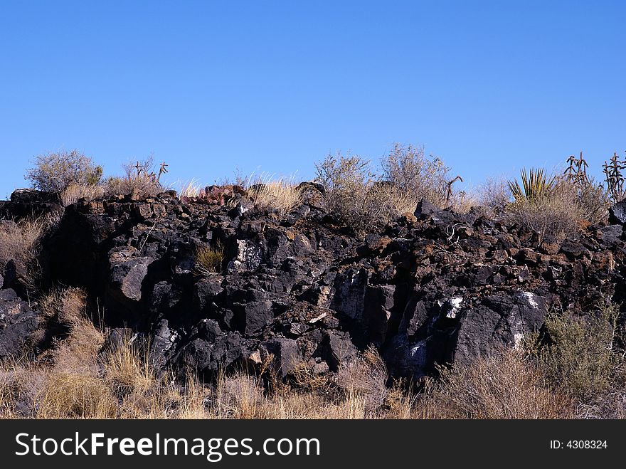 Wall of lava rocks under deep blue sky in The Valley of Fire, central New Mexico USA.