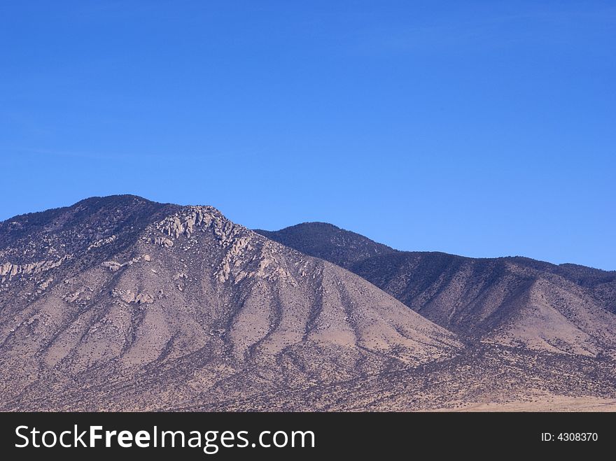 Textured mountains against deep blue sky in central New Mexico USA.