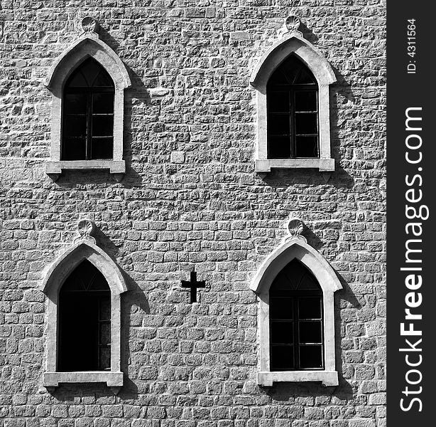 Brick wall with gothic windows and cross. B&W image.