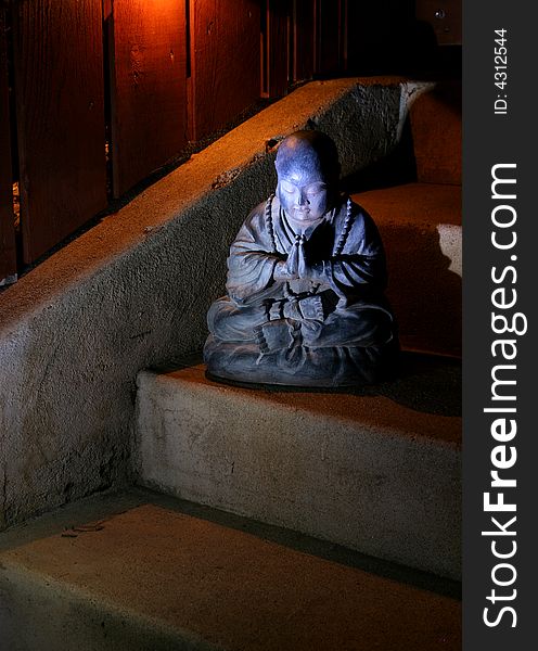 A praying Buddha statue glows in the moonlight. A praying Buddha statue glows in the moonlight