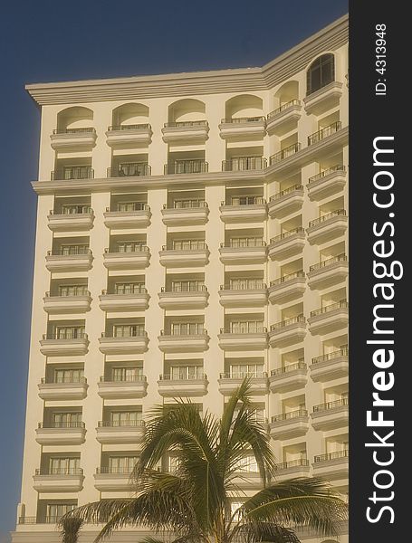 A large white resort hotel in the tropics with palm trees. A large white resort hotel in the tropics with palm trees