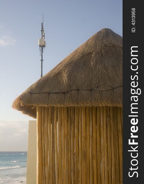 Electronics and antenna on the roof of a bamboo and straw hut at the beach. Electronics and antenna on the roof of a bamboo and straw hut at the beach