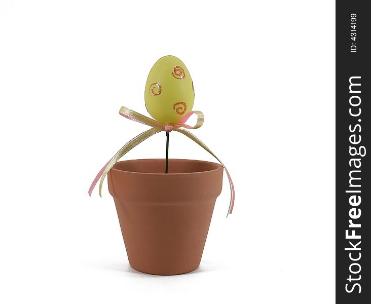 A decorated yellow Easter egg grows out of a terracotta flowerpot. A decorated yellow Easter egg grows out of a terracotta flowerpot.