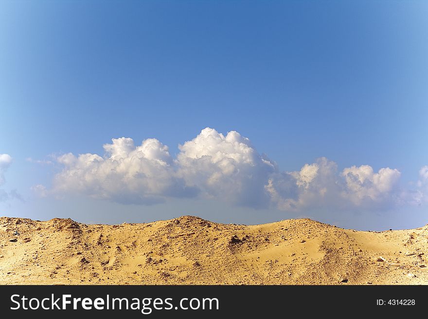 Sandy dune. The blue sky. Clouds