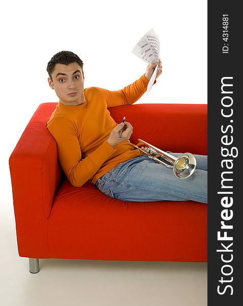 Trumpeter sitting on red couch and composing music, holding sheet music in hands.  Looking at camera. White background. Trumpeter sitting on red couch and composing music, holding sheet music in hands.  Looking at camera. White background.