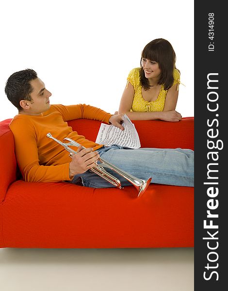 The man sitting on couch and holding trumpet and sheet music in hands. The woman standing behind couch. They're looking at each other. White background. The man sitting on couch and holding trumpet and sheet music in hands. The woman standing behind couch. They're looking at each other. White background.