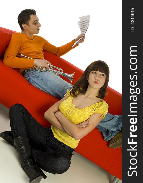 The woman sitting beside couch and looks insulted. The man sitting on the couch and looking at sheet music. White background. The woman sitting beside couch and looks insulted. The man sitting on the couch and looking at sheet music. White background.