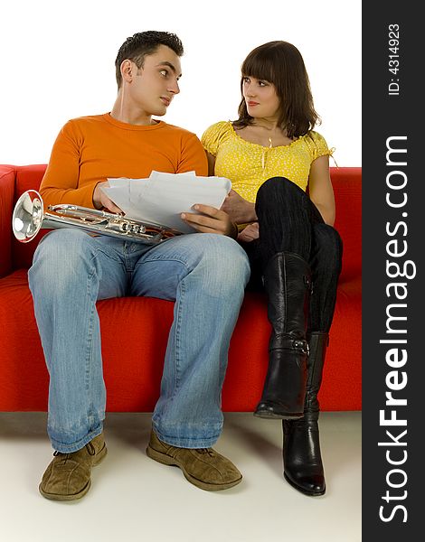 The man and the woman sitting on red couch, talking and looking at each other. Man showing the woman sheet music. Front view. White background. The man and the woman sitting on red couch, talking and looking at each other. Man showing the woman sheet music. Front view. White background.