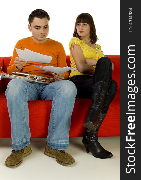 The man and the woman sitting on red couch. Man showing the woman sheet music. She looks insulted. White background. The man and the woman sitting on red couch. Man showing the woman sheet music. She looks insulted. White background.