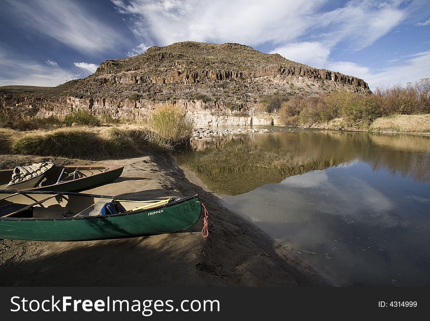 Two canoes prepare to go out on the Rio Grande River in Texas near some mountains. Two canoes prepare to go out on the Rio Grande River in Texas near some mountains.