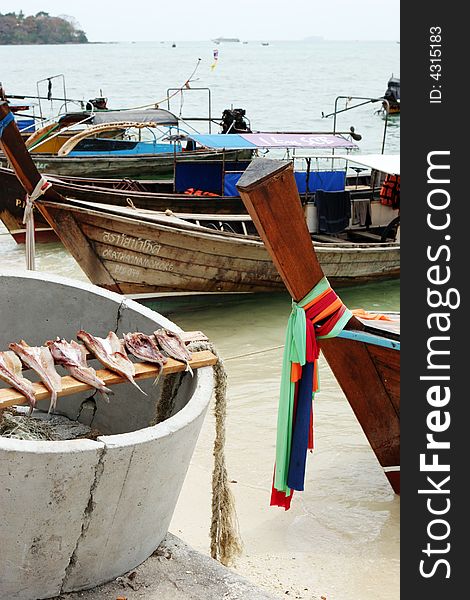 Fish out to dry with fishing boats in the background, Phi Phi Island, Thailand - travel and tourism. Fish out to dry with fishing boats in the background, Phi Phi Island, Thailand - travel and tourism.