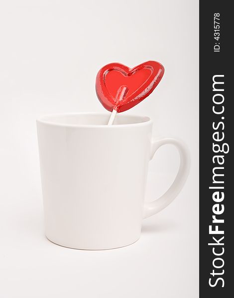 Cup with heart shape lollipop on a white background
