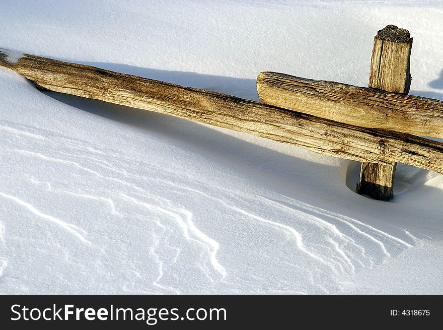 Snow drift buries split rail fence in wind-swept field. Snow drift buries split rail fence in wind-swept field