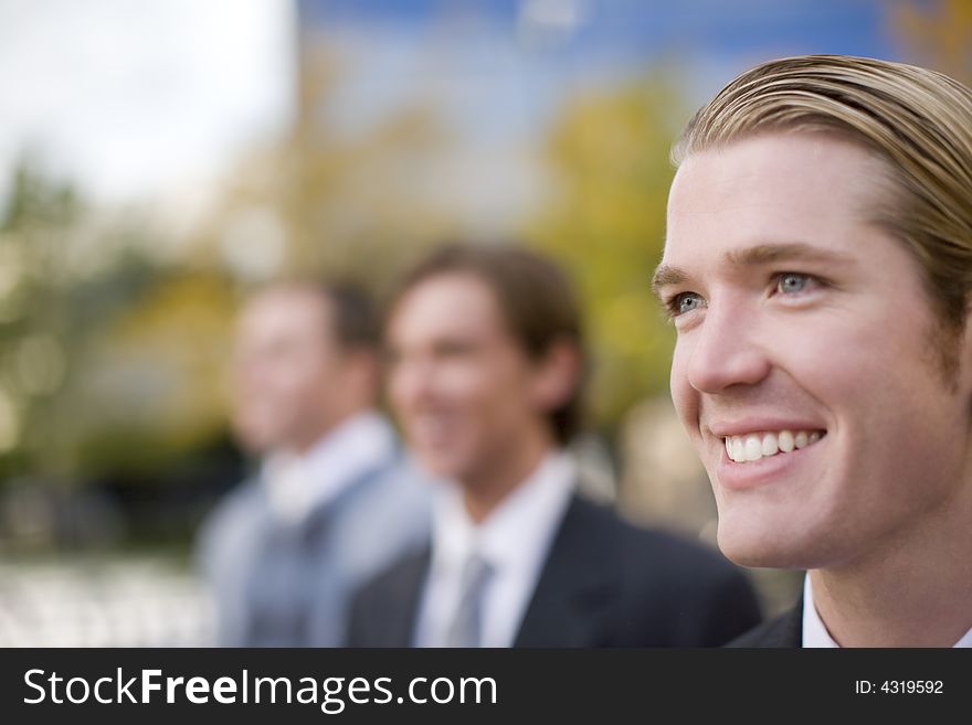 Three business men standing and smiling in same direction. Three business men standing and smiling in same direction