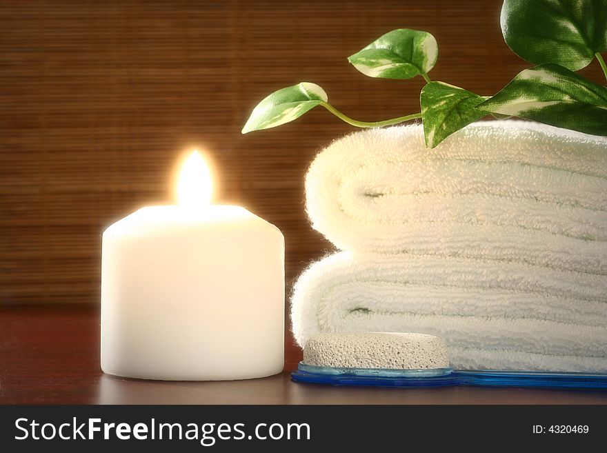 White candle and towel, green leaf and pumice in front of bamboo blind. White candle and towel, green leaf and pumice in front of bamboo blind