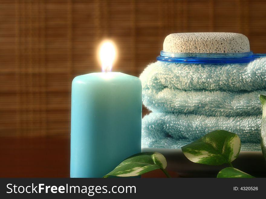 Blue candle and towel, green leaf and pumice in front of bamboo blind. Blue candle and towel, green leaf and pumice in front of bamboo blind