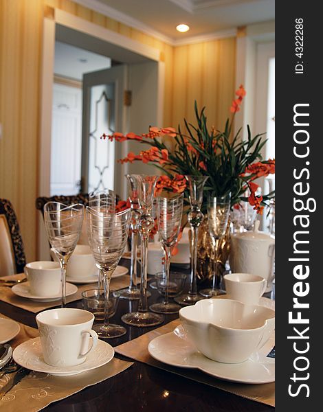 A table with many plates bowls and glasses in luxury dining room.