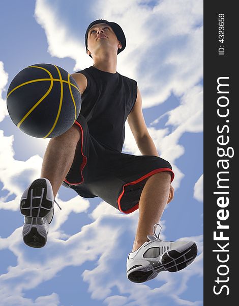 Young basketball player dribbling ball. Looking at something. Low angle view. Young basketball player dribbling ball. Looking at something. Low angle view