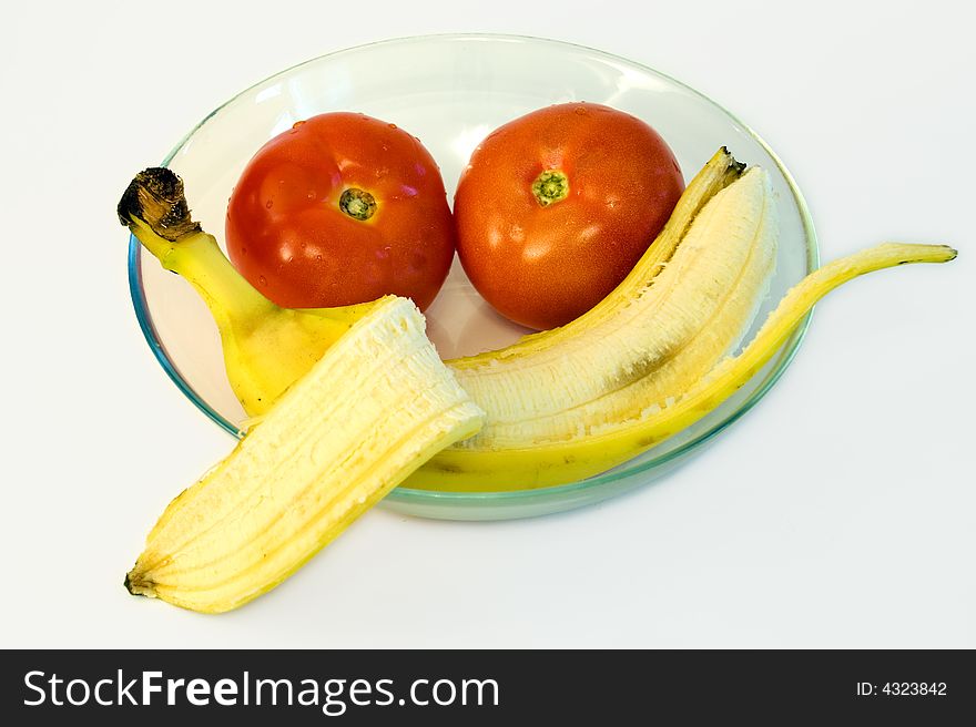 Peeled banana with  tomatoes on glass plate on white background. Peeled banana with  tomatoes on glass plate on white background