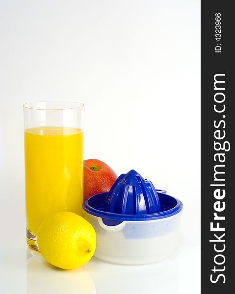 Big transparent glass of orange juice, yellow lemon, red apple and squeezer on white background. Big transparent glass of orange juice, yellow lemon, red apple and squeezer on white background