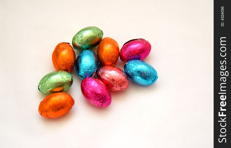 Colourful selection of minature foil wrapped chocolate easter eggs on white background