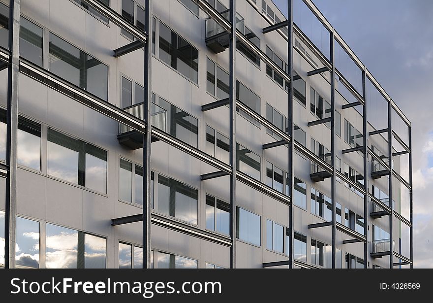 Modern office building with window and balcony, against blue sky.