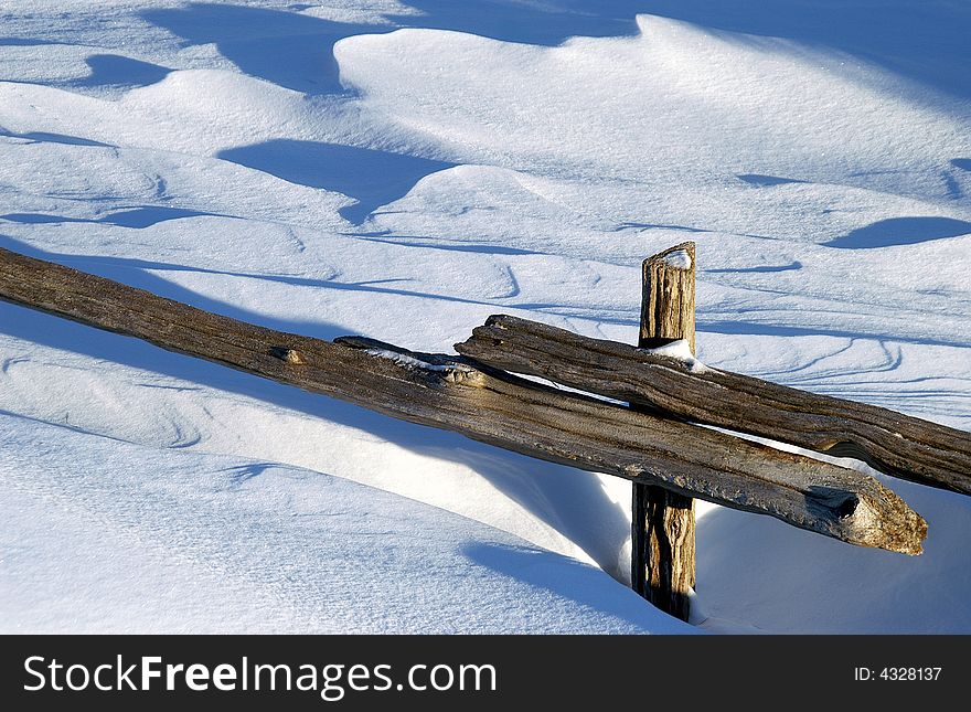 Snow drift buries split rail fence in wind-swept field. Snow drift buries split rail fence in wind-swept field