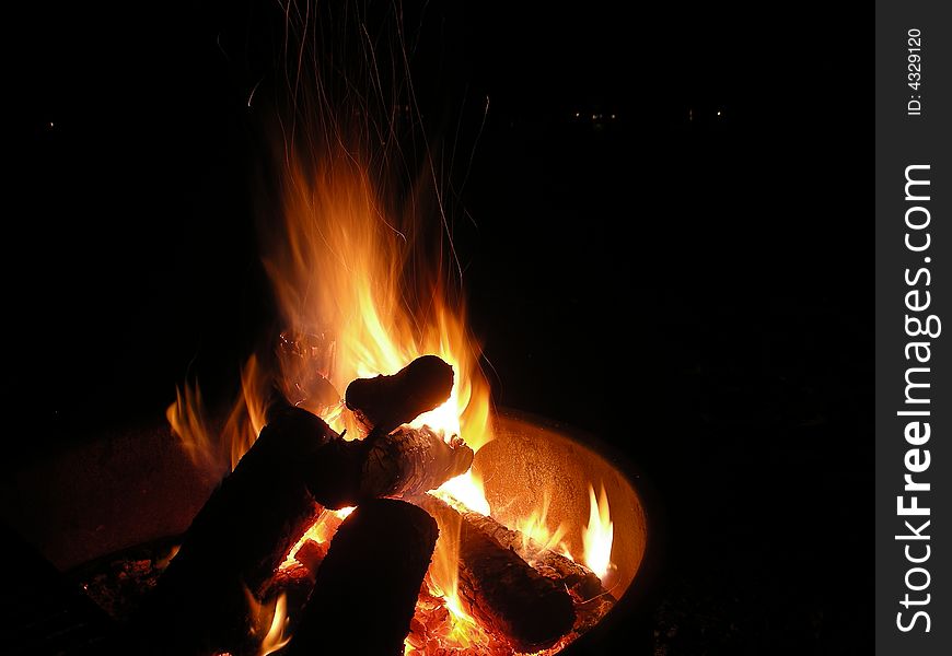 Campfire burning inside a fire-ring as found at many campgrounds. Campfire burning inside a fire-ring as found at many campgrounds