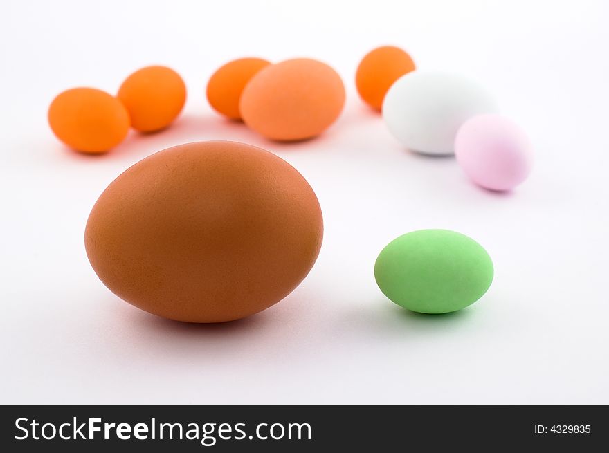 Big egg near little green Easter egg with colored eggs in the background isolated on white. Big egg near little green Easter egg with colored eggs in the background isolated on white