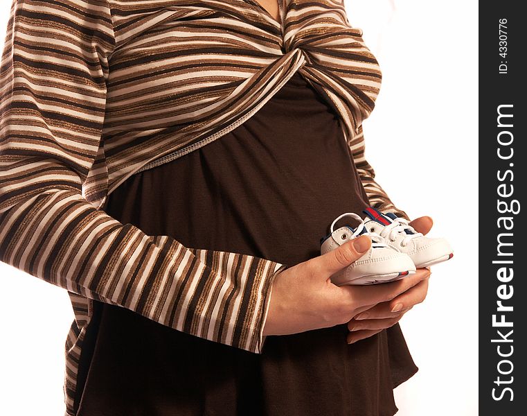 The pregnant woman on a white background. In hands holds small boots