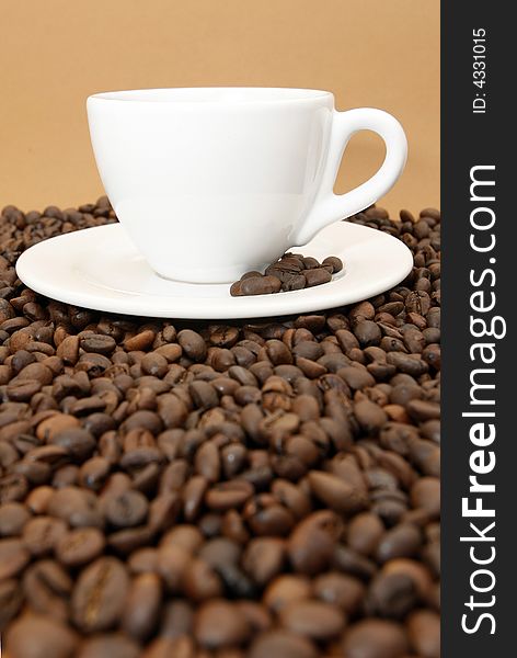 White coffee cup with coffee beans on brown background