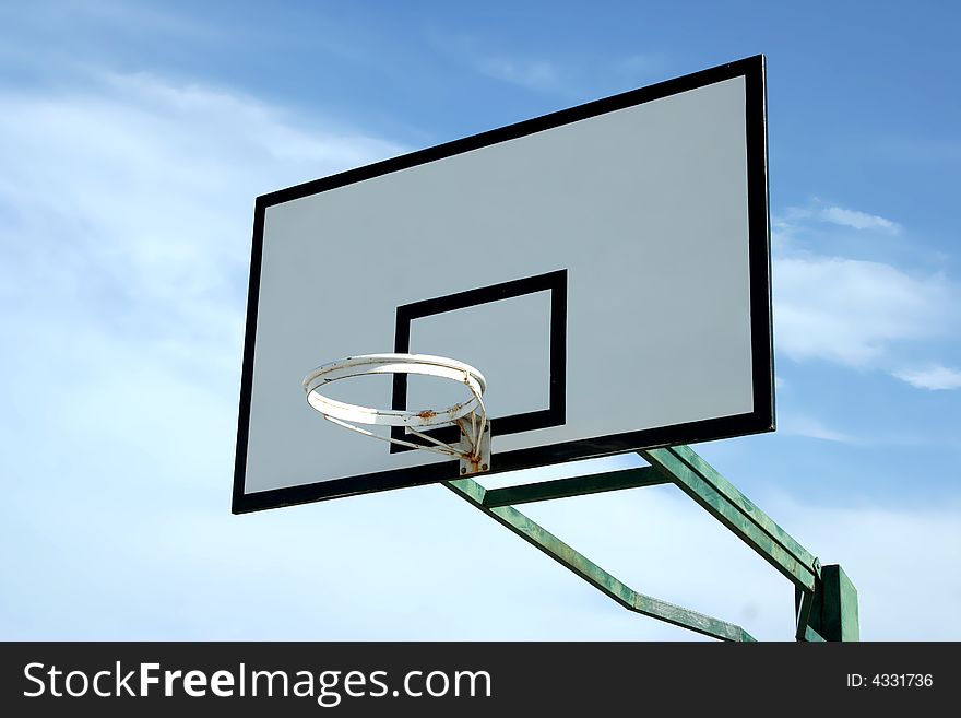 Old basketball basket in blue sky with some clouds