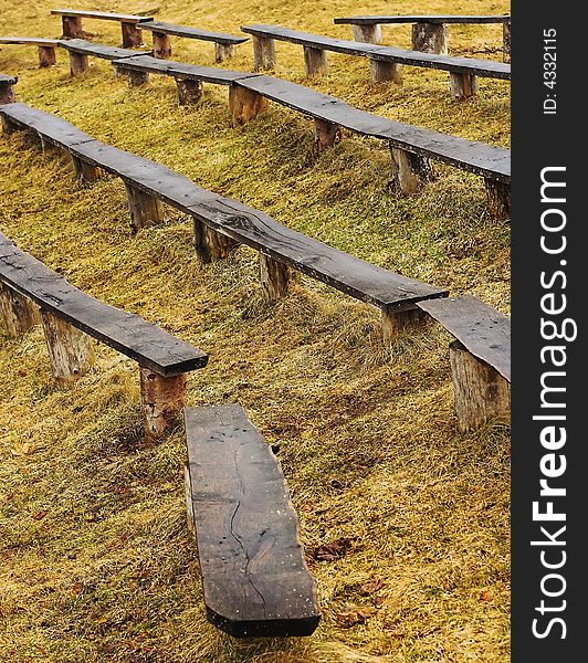 Old benches in a rows with yellow grass on background