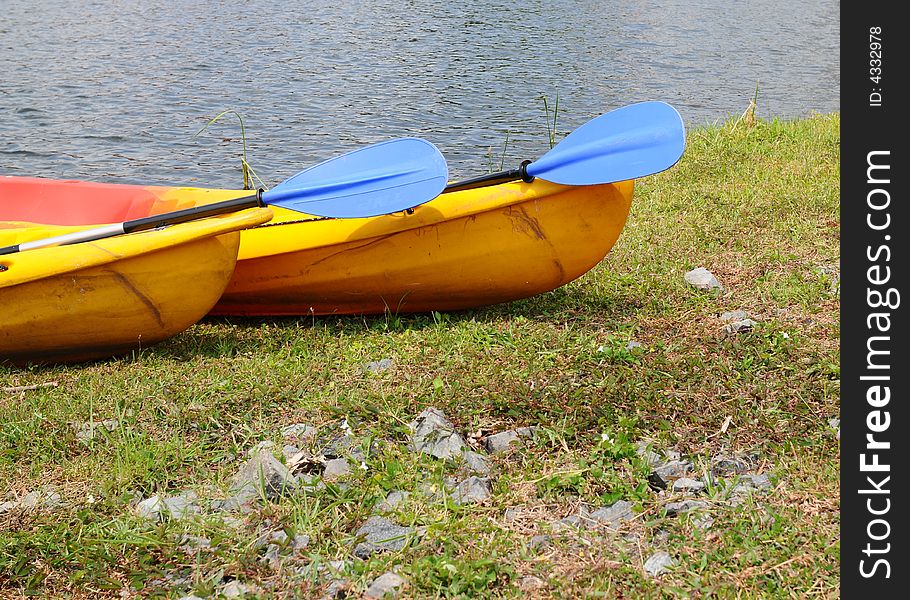 Two kayak in a similar stationary position with their oars pointing the same way. Two kayak in a similar stationary position with their oars pointing the same way