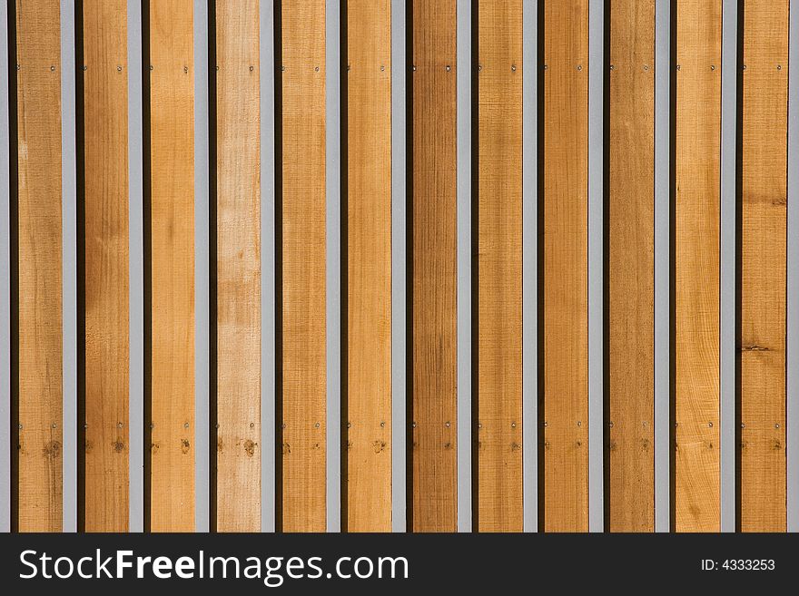 The horizontal striping of a wood and metal gate.