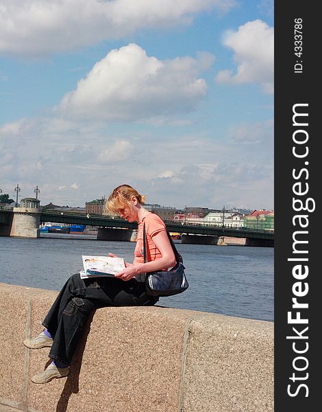 Girl reading magazine on canal border