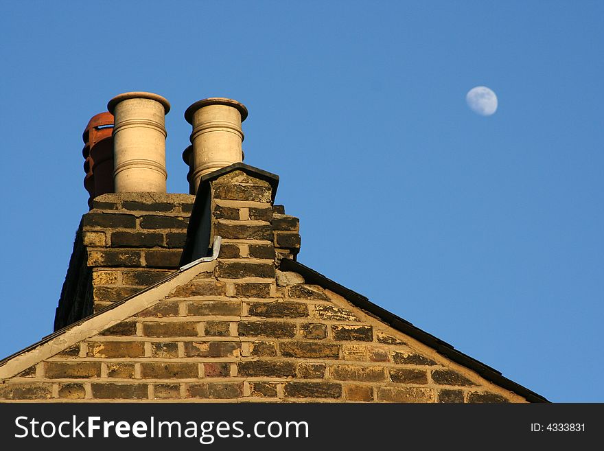 This is a shot of an old building in London with the moon out in the daytime. This is a shot of an old building in London with the moon out in the daytime