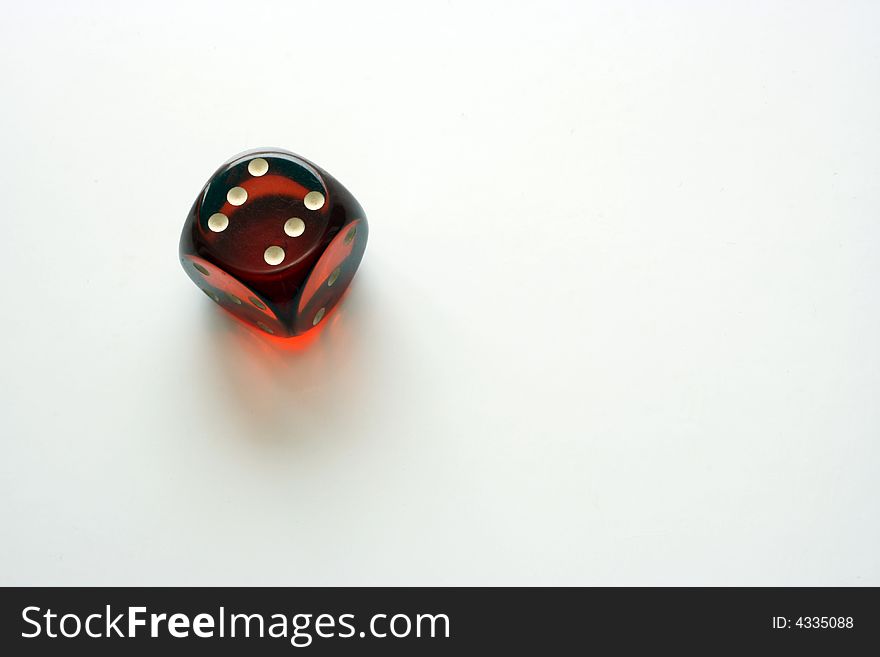A glass die cube with a six on it on a white background. A glass die cube with a six on it on a white background