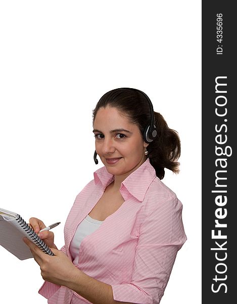 A girl, wearing headphones and microphone, taking notes, smiling. A girl, wearing headphones and microphone, taking notes, smiling