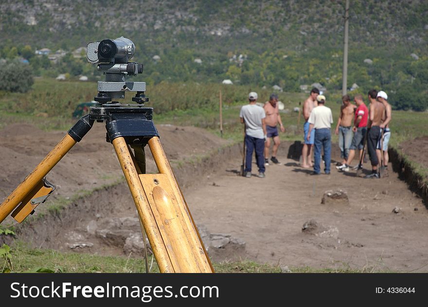 Group working on archeological site with theodolite